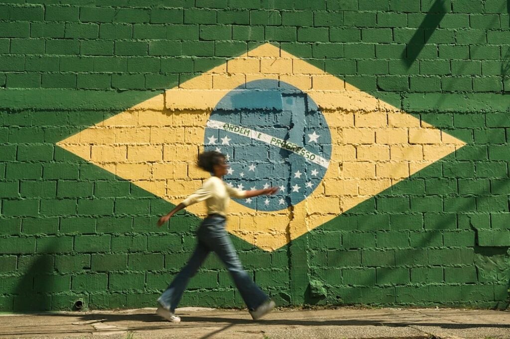 Girl Walking on Street with Brazilian Flag on Wall